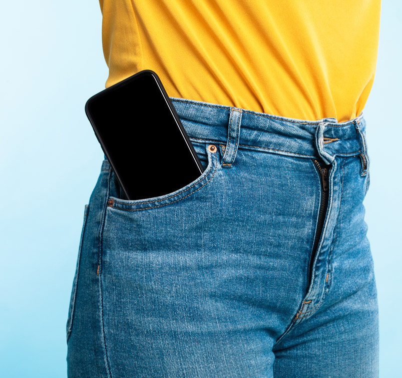 Frau trägt ein großes Smartphone in ihrer Jeanshosentaschen.