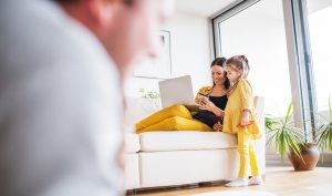 Mutter mit kleiner Tochter auf dem Sofa im Wohnzimmer.